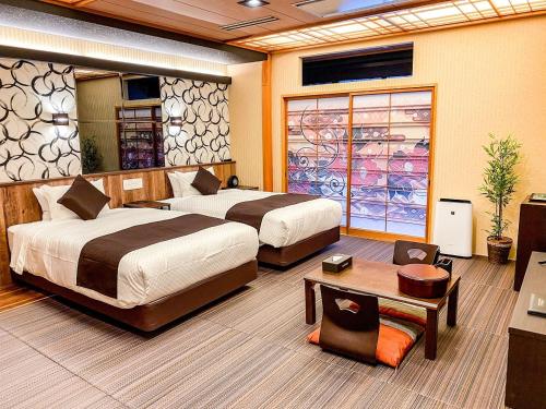 松山的住宿－LiVEMAX RESORT Okudogo，酒店客房设有两张床和一张桌子。