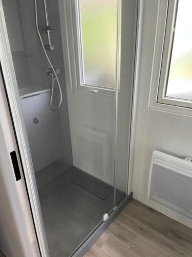 une douche avec une porte vitrée dans une salle de bain dans l'établissement GHVacances Le PiPiou, à Parentis-en-Born