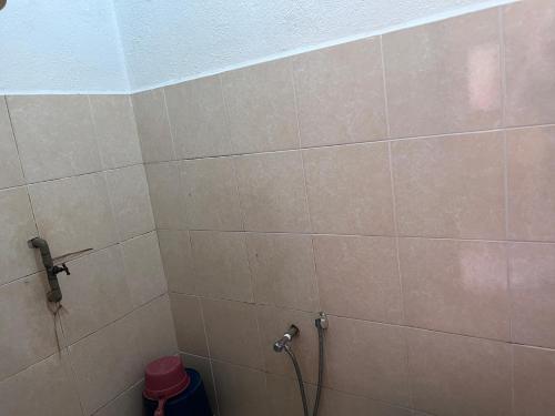 a bathroom with a shower with a tiled wall at OYO 90981 Chenang Rest House 1 in Pantai Cenang
