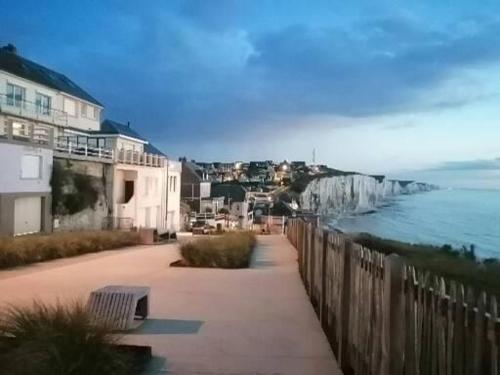 un banc assis sur un trottoir à côté de l'océan dans l'établissement Studio vue mer, à Ault