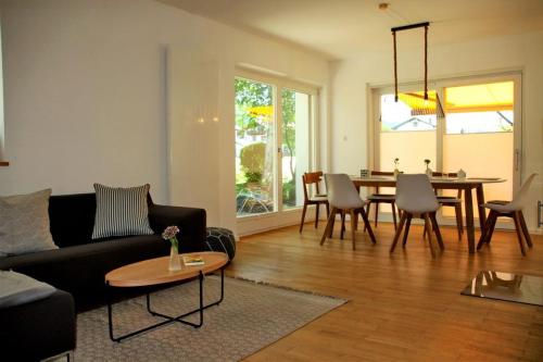 un soggiorno con divano nero e tavolo di Birkenwind a Bernau am Chiemsee