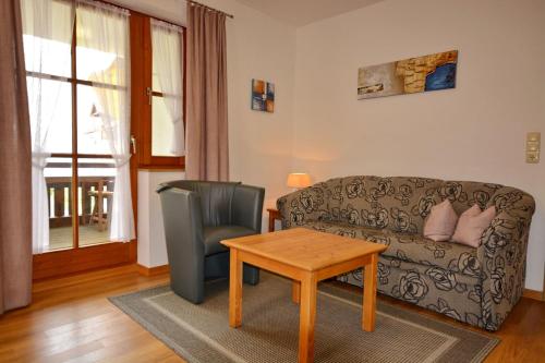 een woonkamer met een bank, een tafel en een stoel bij Ferienresidenz Chiemseestrand - Apartment 28 in Chieming