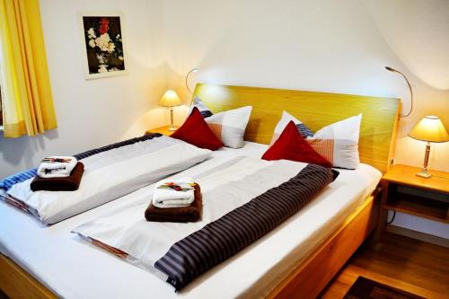 2 bedden in een hotelkamer met witte en rode kussens bij Ferienresidenz Chiemseestrand - Chiemseesonne in Chieming