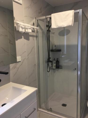 a bathroom with a shower and a sink at West Auckland Delight Stay in Auckland