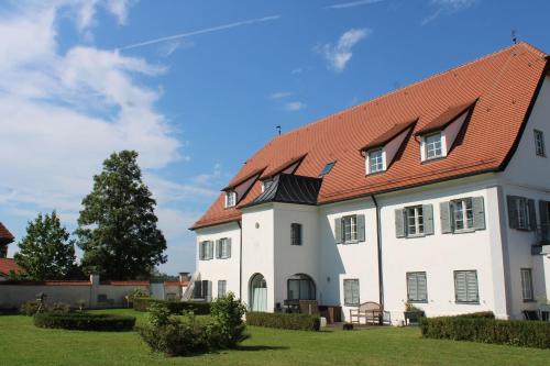 een groot wit huis met een rood dak bij Schloss Winkl in Grabenstätt