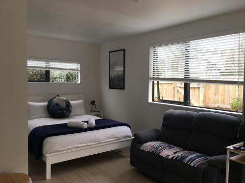 West Auckland Delight Stay في أوكلاند: غرفة نوم بسرير واريكة ونافذة