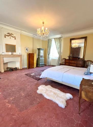 une chambre avec un grand lit et un lustre dans l'établissement Maison de famille Jacqueline, à Vitteaux