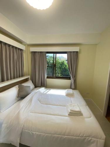 a large white bed in a room with a window at Kata beach townhouse in Kata Beach