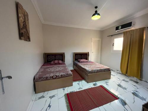 two beds in a room with two rugs on the floor at Nubian Villa with Private Pool in Naj‘ al Aḩwāl