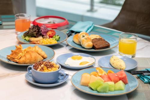 Crowne Plaza Wuhan Optics Valley, an IHG Hotel في ووهان: طاولة مع أطباق من طعام ومشروبات الإفطار
