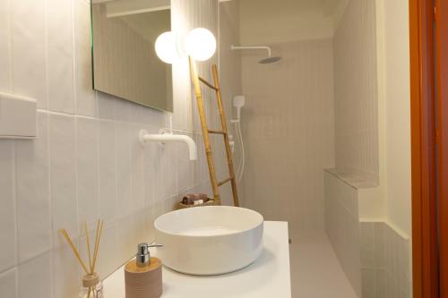 uma casa de banho branca com um lavatório e um espelho em RaíZes 22 - Apartamento 6 em Puebla de Don Fadrique