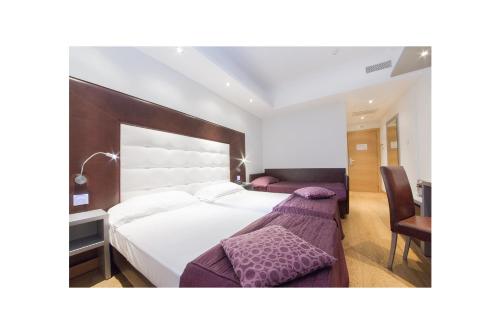 una camera con un grande letto bianco e una scrivania di Hotel Royal Caserta a Caserta