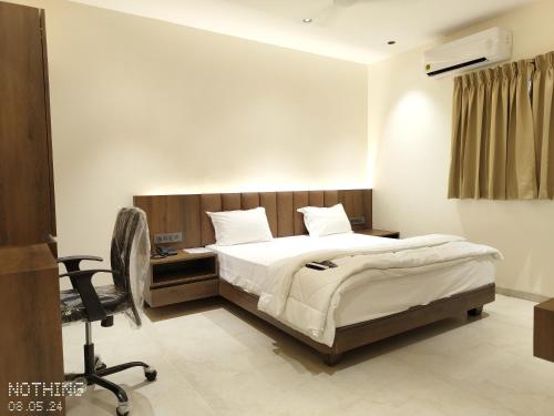 een slaapkamer met een bed, een bureau en een stoel bij HOTEL 3T WORLD in Nanded