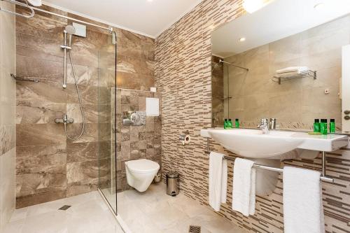 W łazience znajduje się toaleta z umywalką i prysznic. w obiekcie Hotel Compliment w mieście Trjawna