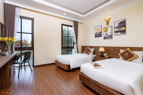 a hotel room with two beds and a desk at Passion Hotel HaLong in Ha Long