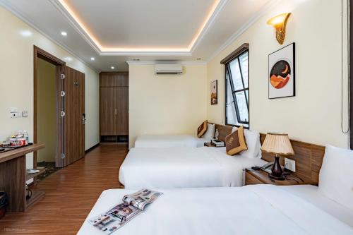 a hotel room with two beds and a desk at Passion Hotel HaLong in Ha Long