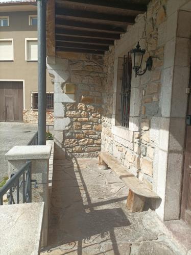 a stone building with a wooden bench next to a wall at La Casona de Ardines in Arenas de Cabrales