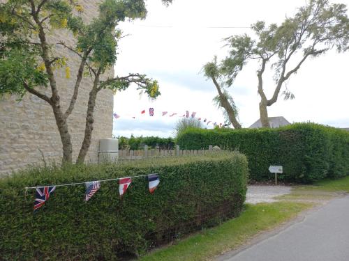 a row of british flags hanging on a hedge at Ivy House Utah Beach in Sainte-Marie-du-Mont