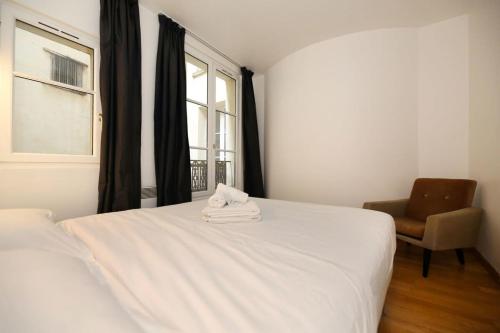 - une chambre avec un lit blanc, une chaise et une fenêtre dans l'établissement 106- Appartement lumineux face jardins des Plantes - FLAT-GUEST, à Paris
