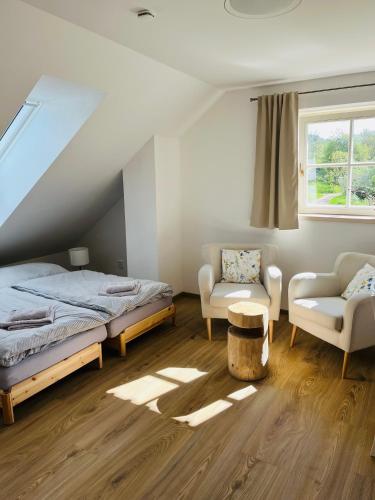a bedroom with a bed and a chair and a window at Apartmány Pernek in Horní Planá