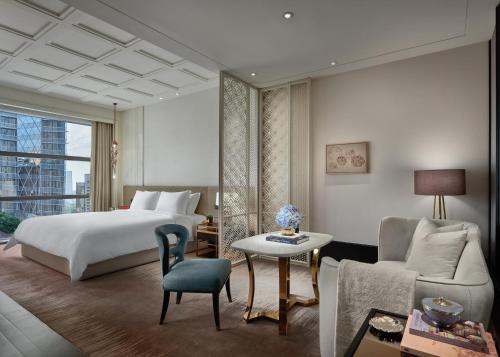 a bedroom with a bed and a couch and a table at Rosewood Bangkok in Bangkok