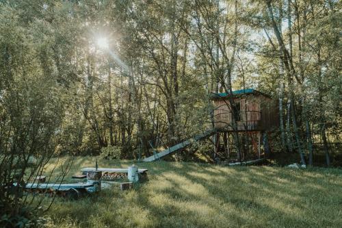 einem Picknicktisch und einer Bank auf einem Feld mit Bäumen in der Unterkunft Treehouse Tučapy in Tučapy