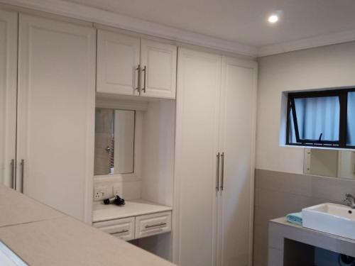 eine weiße Küche mit weißen Schränken und einem Waschbecken in der Unterkunft Zur See - 50m2 Private apartments with Braai - Self catering in Ballito