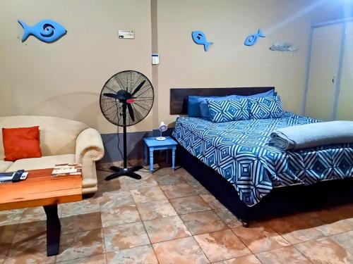 ein Schlafzimmer mit einem Bett, einem Stuhl und einem Ventilator in der Unterkunft Zur See - 50m2 Private apartments with Braai - Self catering in Ballito