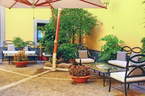 a patio with chairs and tables with plants and an umbrella at Le Cheminée Business Hotel Napoli in Naples