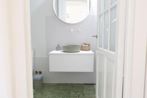 uma casa de banho branca com um lavatório e um espelho em RaíZes 22 - Apartamento 5 em Puebla de Don Fadrique