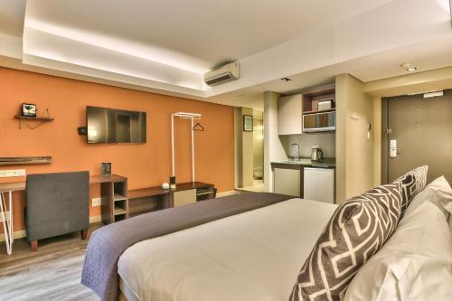 um quarto de hotel com uma cama grande e uma cozinha em WINK Aparthotel Foreshore em Cidade do Cabo