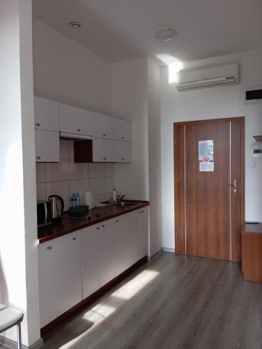 a kitchen with white cabinets and a wooden door at Apart in Radomsko