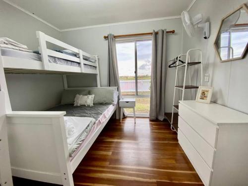 ein Schlafzimmer mit zwei Etagenbetten und einem Fenster in der Unterkunft Pet & Family Friendly Ocean Front Beach Cottage in Bargara