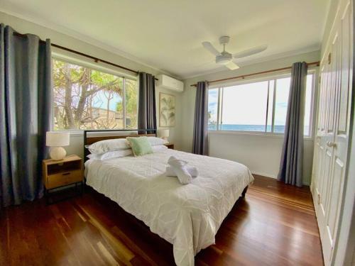 ein Schlafzimmer mit einem großen Bett und einem großen Fenster in der Unterkunft Pet & Family Friendly Ocean Front Beach Cottage in Bargara