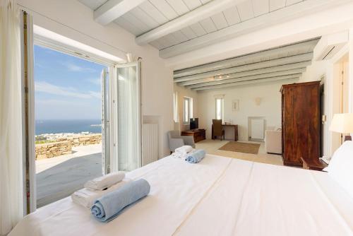 a bedroom with a large white bed and a large window at TLuxuryvilla in Parikia