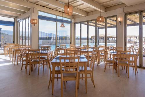 uma sala de jantar com mesas, cadeiras e janelas em Neptuno Beach Hotel em Amoudara Herakliou