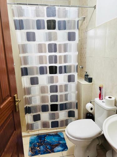 a bathroom with a toilet and a shower curtain at Cozy Retreat Near Nairobi National Park, Giraffe Centre & Wilson Airport in Nairobi