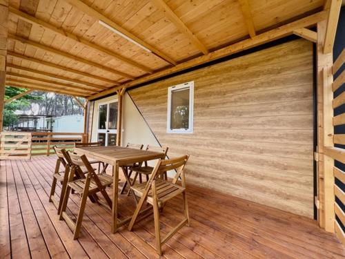 una terraza de madera con mesa y sillas. en ISOLA VERDE Camping Village, en Nettuno