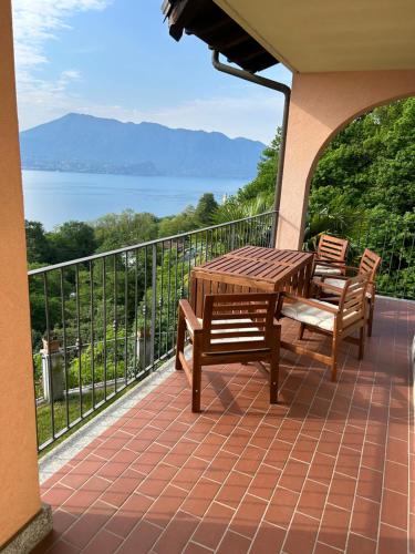 a patio with a wooden table and chairs on a balcony at Lago Maggiore - Traumbalkon mit Seeblick & Pool und 2 SZ in Oggebbio