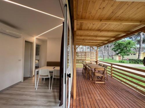 una terraza con mesas y sillas y techo de madera. en ISOLA VERDE Camping Village en Nettuno