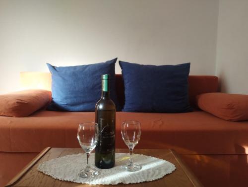 a bottle of wine and two wine glasses on a table at Apartman Tri palme in Gabonjin