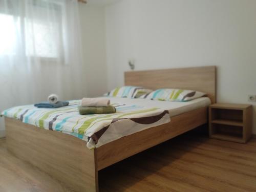 a bedroom with a bed with a wooden headboard at Apartman Tri palme in Gabonjin