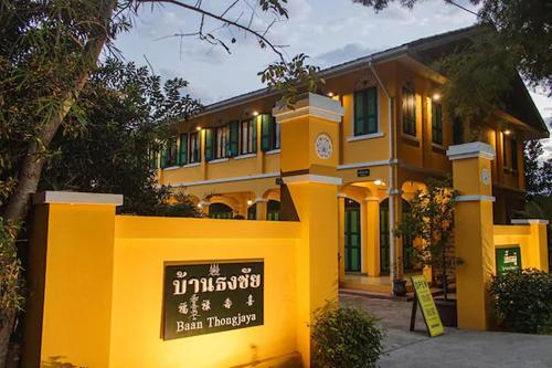 a yellow building with a sign in front of it at Bhirom at Baan Thongjaya in Ban Fon