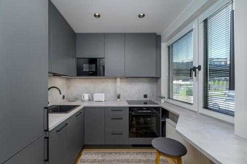 a kitchen with gray cabinets and a sink and a chair at New apartment near the airport, city center in Sikupilli in Tallinn