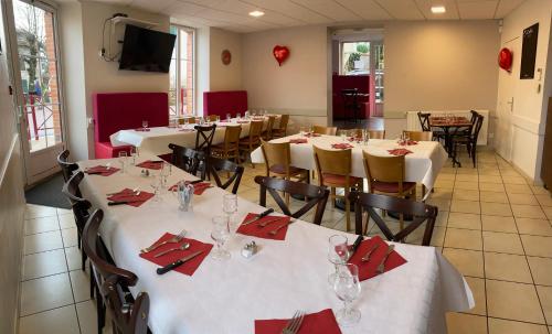 a dining room with white tables and chairs with red napkins at Relais des Monts du Lyonnais in Les Halles