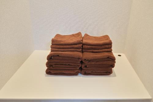 a pile of brown towels sitting on a white table at J-ARC Akebonobashi in Tokyo