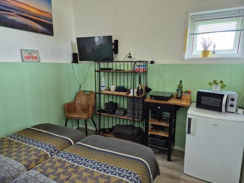 a bedroom with a bed and a television and a desk at Landelijk slapen bij molen in Ovezande 4C in Ovezande