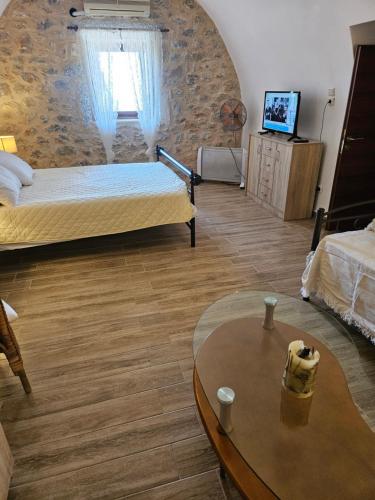 a room with two beds and a table and a tv at Kamares Stone House 1 in Álika