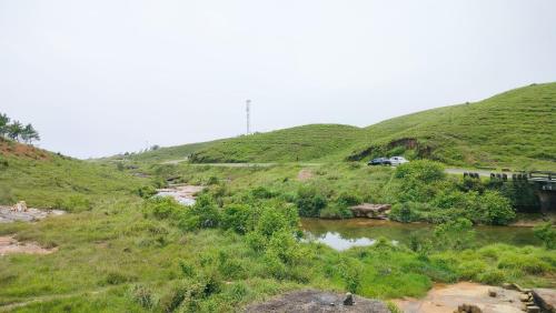 a hill with a river and a car on a road at Iba Homestay in Cherrapunji