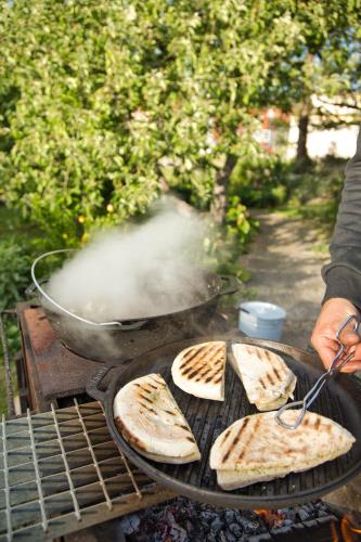 a person is cooking food on a grill at Divas Istabas in Saldus
